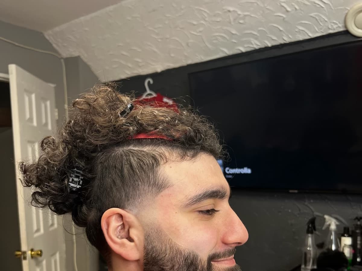 Faded sides with the curls gathered into a top knot and the beard squared off