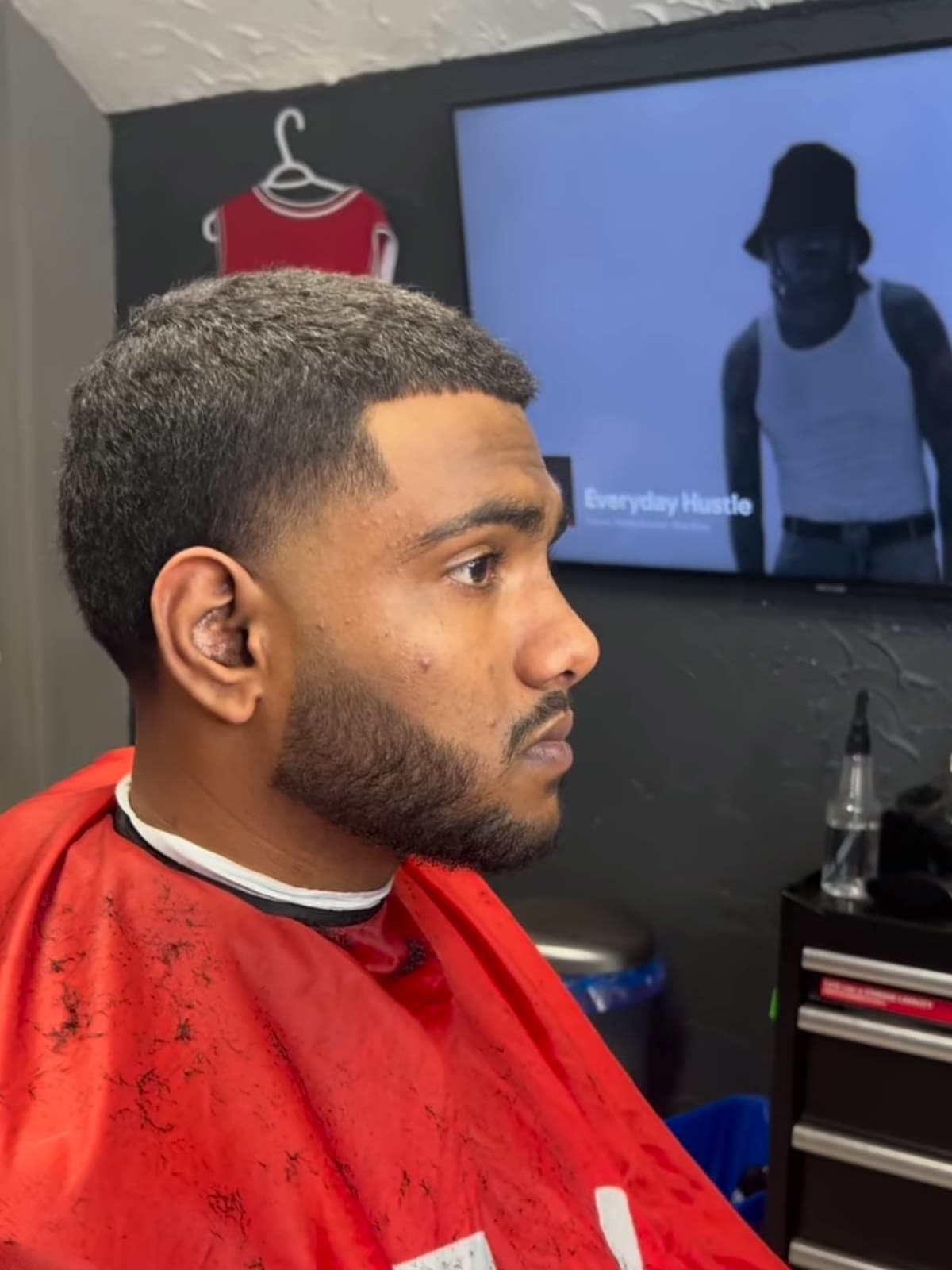 Tight buzz cut with a sharp line-up and a trimmed beard